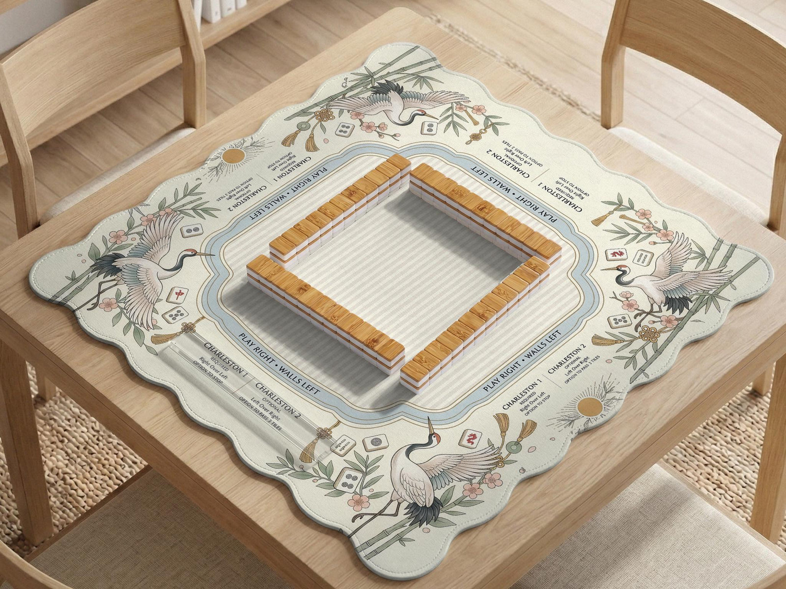 Beige square mahjong mat with a sage border, crane birds, bamboo, flowers, tile icons, and printed rules around a clean center play area.