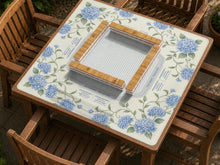 Blue hydrangea flowers and sage green leaves on a cream mahjong mat with a striped center and printed rule text around the border.