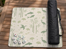 Cream mahjong mat with sage green koi, crane, ginkgo, and bamboo artwork in a repeating decorative layout.