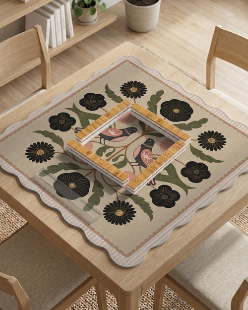 Beige mahjong mat with a botanical floral bird design, blush flowers, olive green leaves, black flower accents, and a warm linen-style background. Scalloped edge option shown.