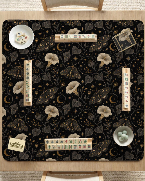 Black square mahjong mat with moths, moonflowers, crescent moons, and scattered stars in a celestial floral pattern.