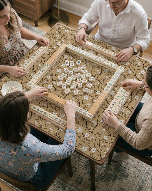 Beige mahjong mat with a white blossom branch floral pattern on a neutral background.