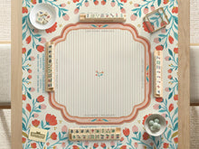 Cream mahjong mat with a coral and teal floral border, rule layout text, Charleston guide notes, and a blank center area for tile play.