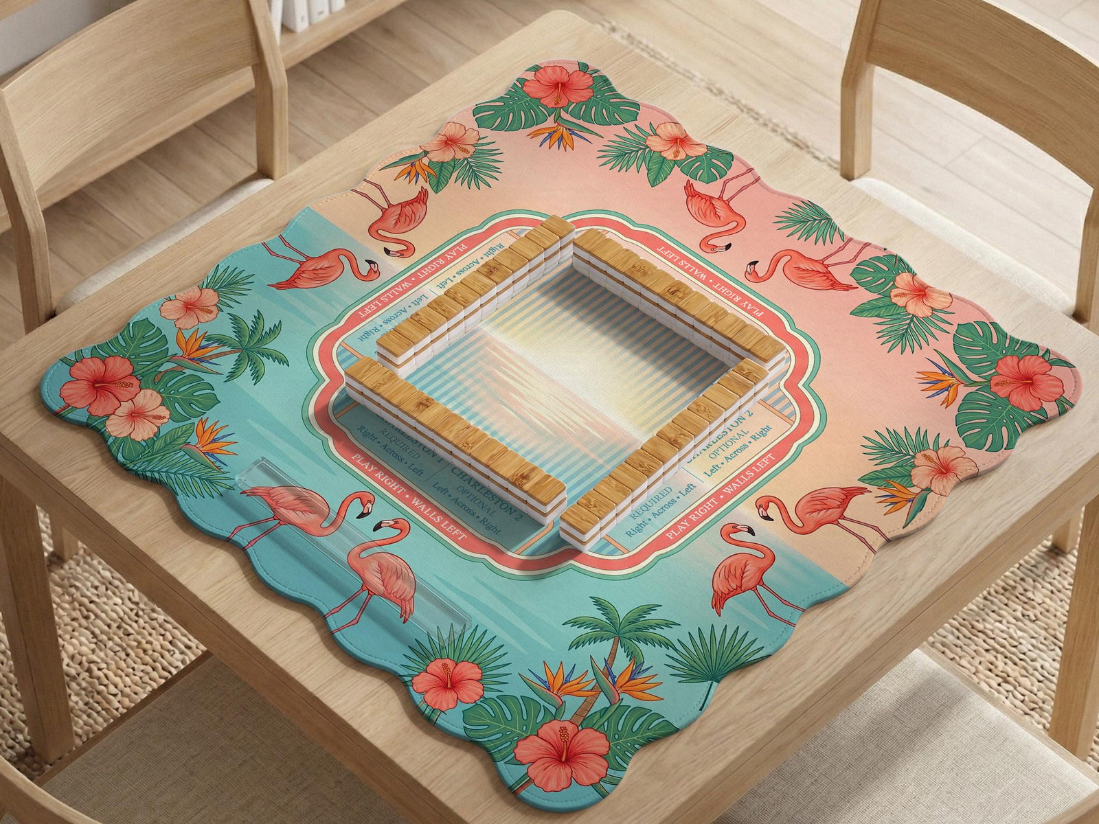 A square mahjong mat with flamingos, hibiscus flowers, palm leaves, and aqua water accents on a coral background with a scalloped edge.