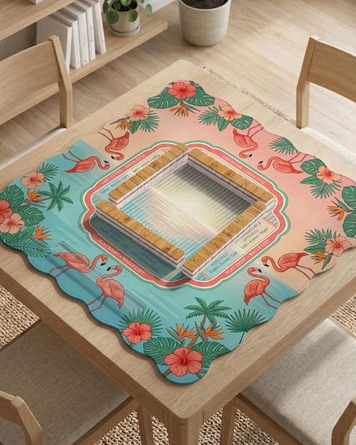 A square mahjong mat with flamingos, hibiscus flowers, palm leaves, and aqua water accents on a coral background with a scalloped edge.