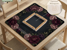 A square mahjong mat with a black background, burgundy peony flowers, and a botanical border around the edges.