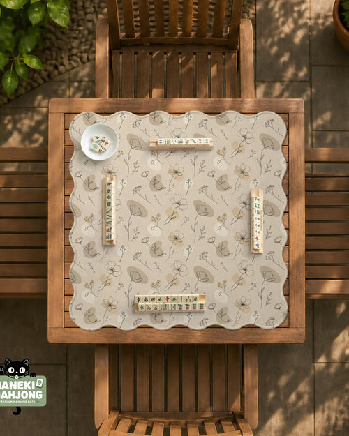 Neutral floral mahjong mat with delicate botanical line art and a scalloped edge on a cream background.