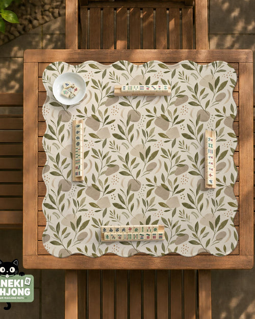 Green botanical mahjong mat with sage leaf and floral design and a scalloped edge.