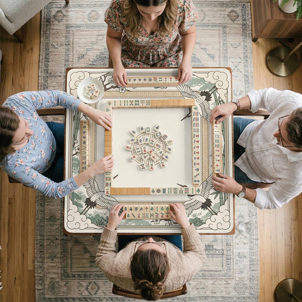 Square mahjong table mat with a cream center and a border design of cranes, bamboo, plum blossoms, and a geometric frame in sage green and warm gold.