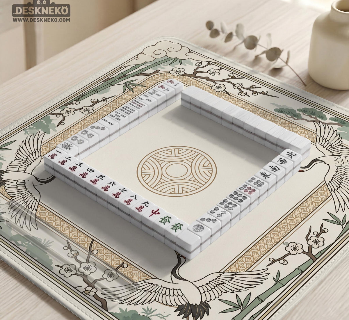 Square mahjong table mat with a cream center and a border design of cranes, bamboo, plum blossoms, and a geometric frame in sage green and warm gold.