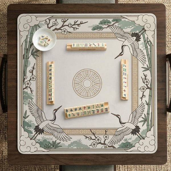 Square mahjong table mat with a cream center and a border design of cranes, bamboo, plum blossoms, and a geometric frame in sage green and warm gold.