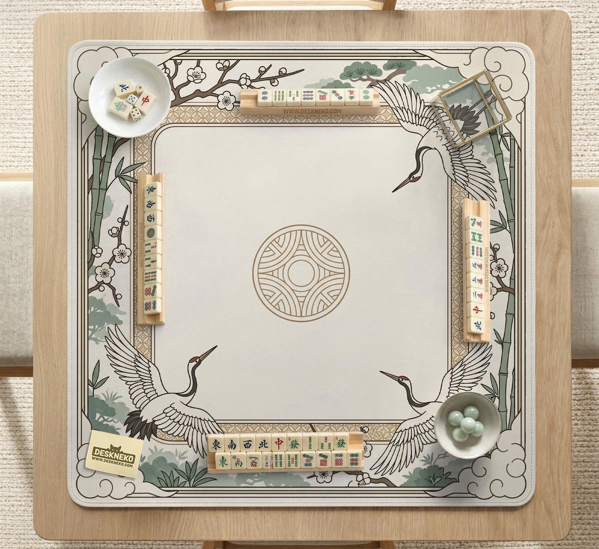 Square mahjong table mat with a cream center and a border design of cranes, bamboo, plum blossoms, and a geometric frame in sage green and warm gold.