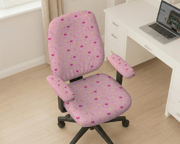 Pink chair cover with a pattern of moons, stars, bows, and small decorative shapes on a chair with armrests.
