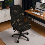 Black chair cover with a dark galaxy pattern, muted gold stars and celestial artwork on a chair.