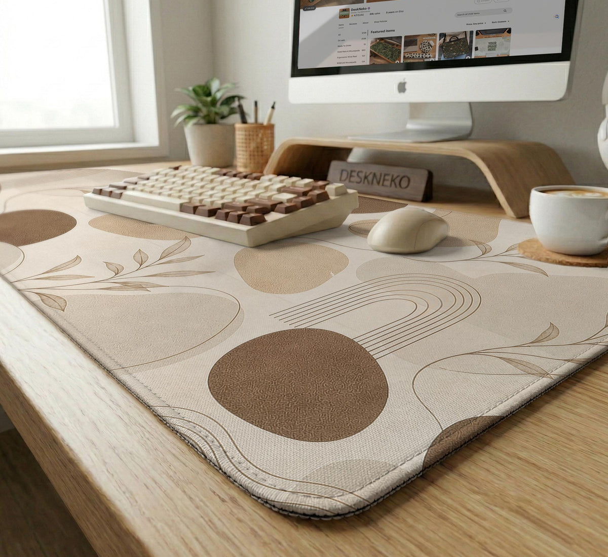 Beige desk mat with fine botanical line drawings and soft abstract shapes on a light neutral background.