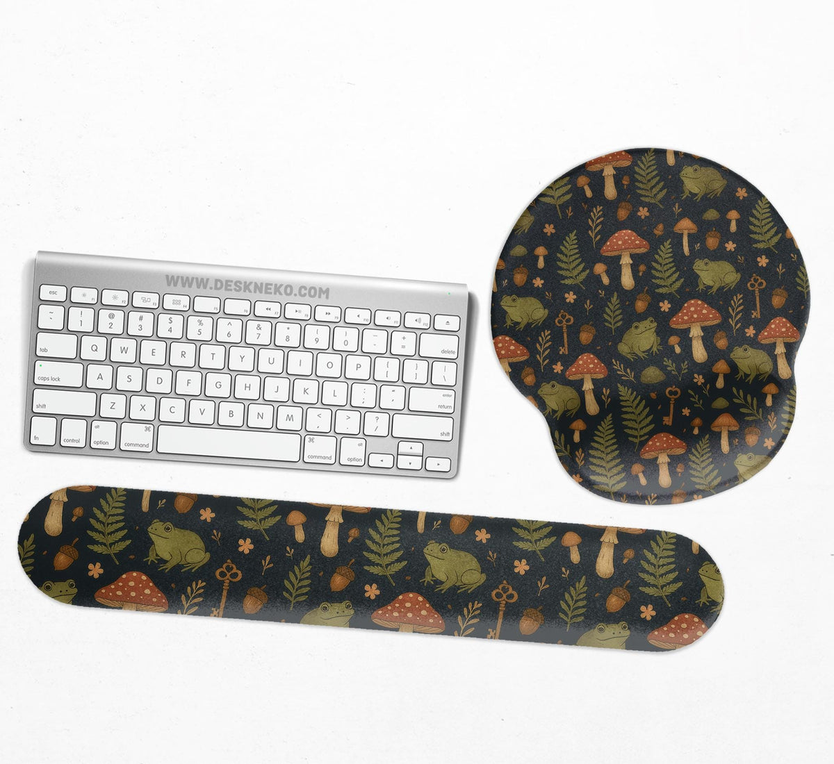 Dark botanical desk mat options with frogs, mushrooms, ferns, and acorns in brown and green tones, plus a matching keyboard wrist rest.