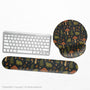 Dark botanical desk mat options with frogs, mushrooms, ferns, and acorns in brown and green tones, plus a matching keyboard wrist rest.