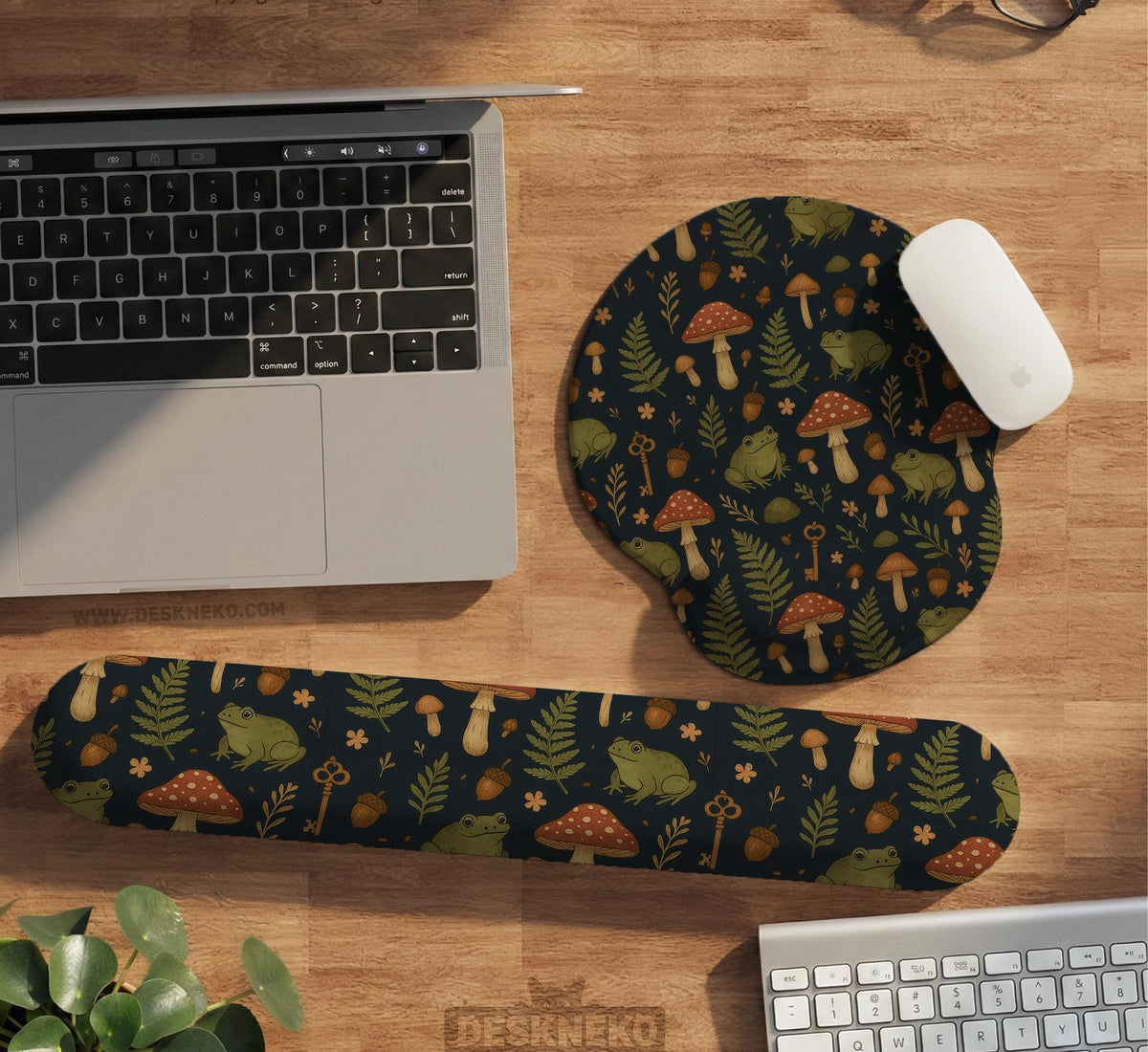 Dark botanical desk mat options with frogs, mushrooms, ferns, and acorns in brown and green tones, plus a matching keyboard wrist rest.