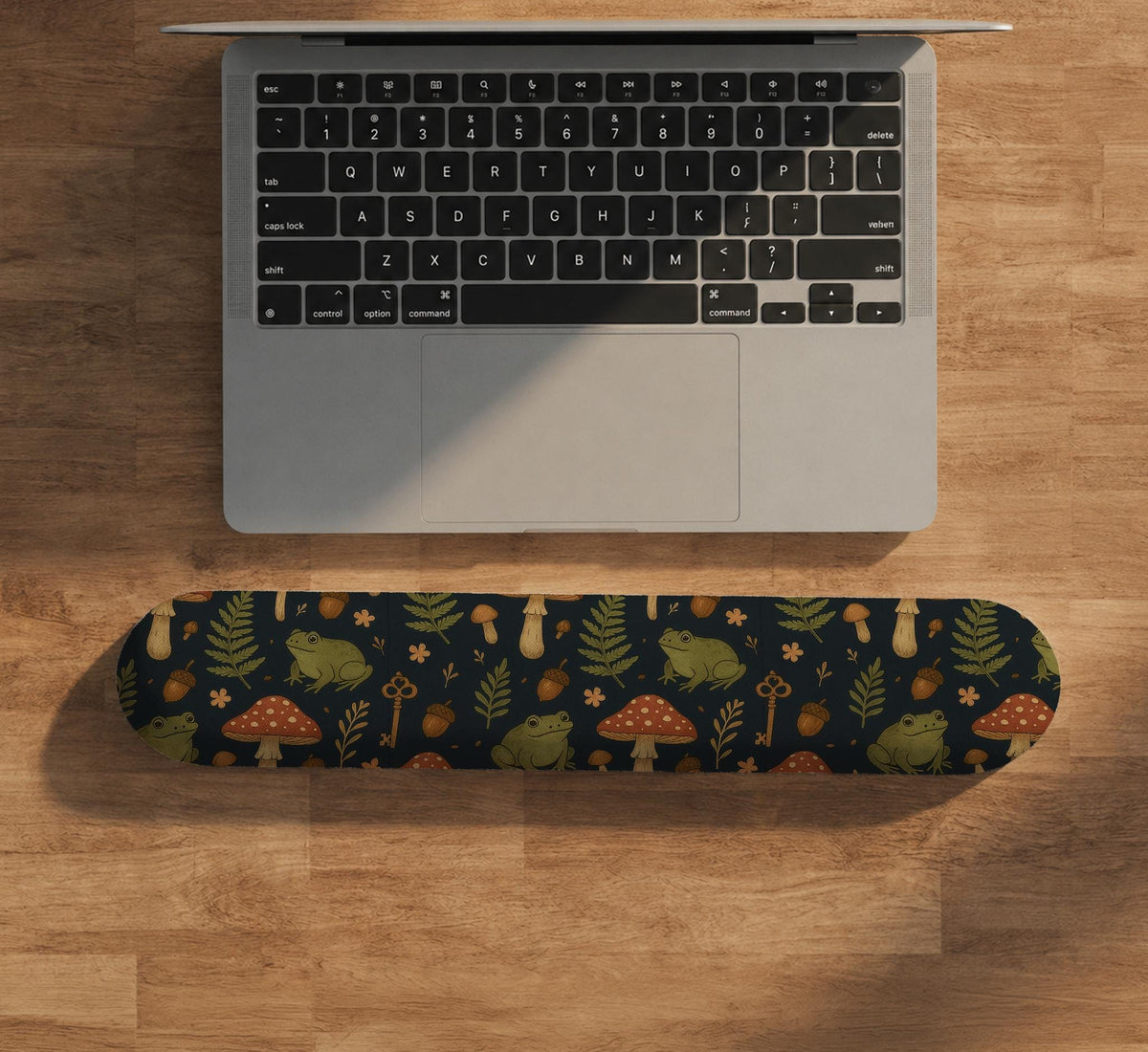 Dark botanical desk mat options with frogs, mushrooms, ferns, and acorns in brown and green tones, plus a matching keyboard wrist rest.