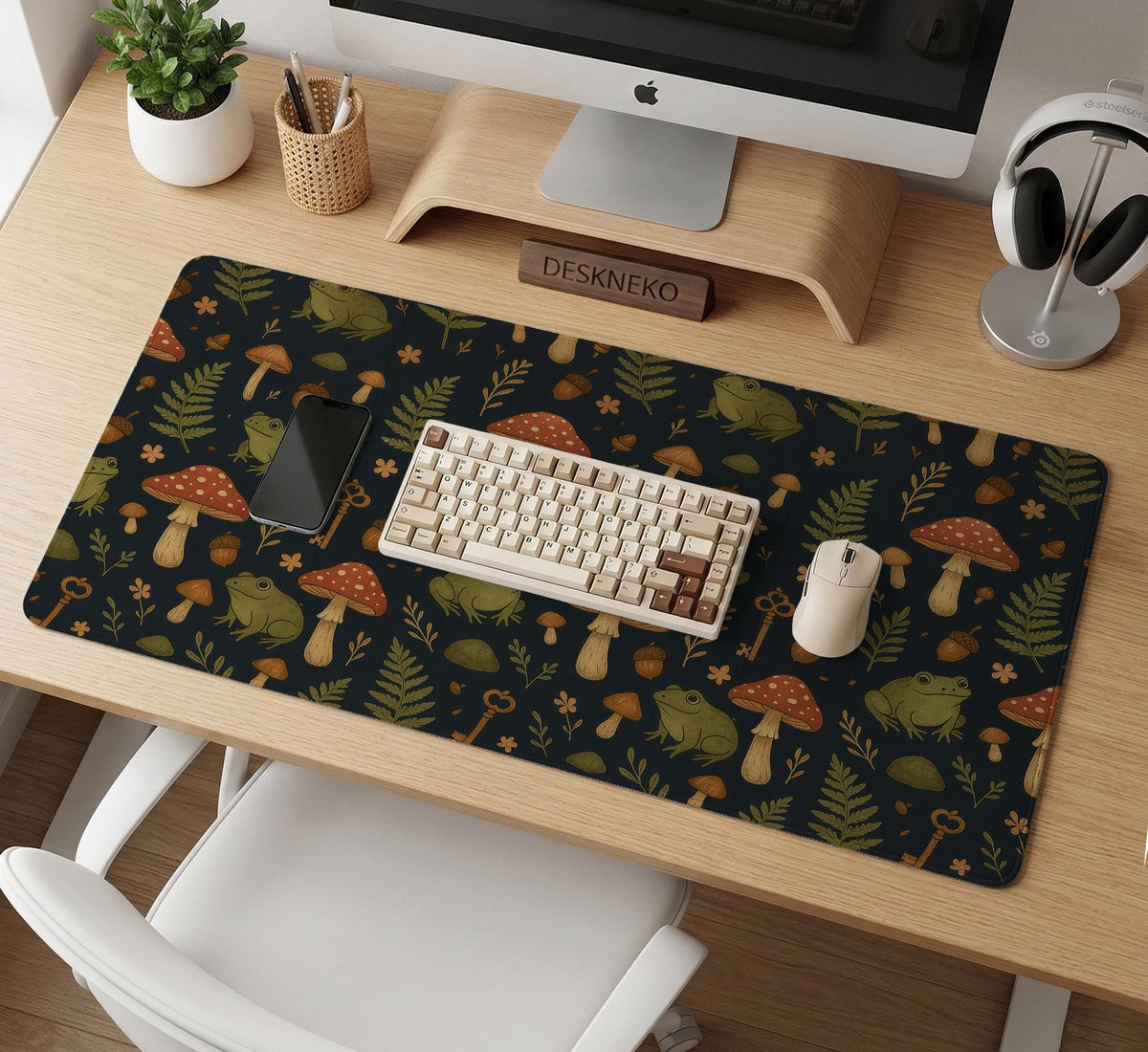 Dark forest-themed desk mat with an all-over pattern of frogs, mushrooms, fern leaves, acorns, tiny flowers, and antique keys.
