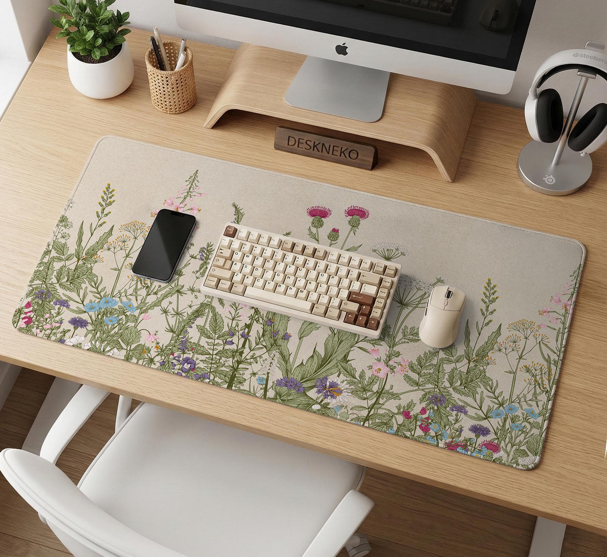 A desk mat with a botanical meadow design featuring wildflowers, leafy stems, and soft neutral colors.