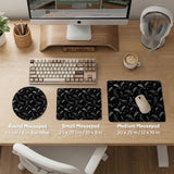 Black desk mat with a dark bat pattern and scattered stars on a charcoal background.