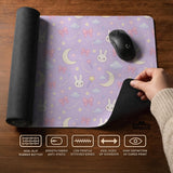 Lavender desk mat with an all-over pattern of bunny faces, clouds, moons, bows, and flowers in pastel colors.