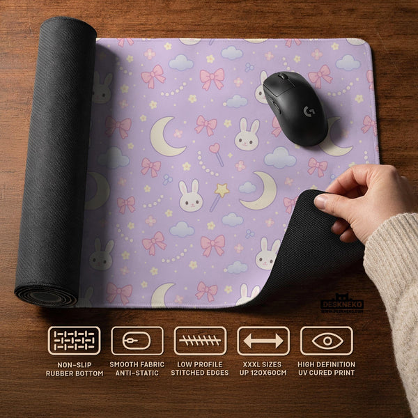 Lavender desk mat with an all-over pattern of bunny faces, clouds, moons, bows, and flowers in pastel colors.