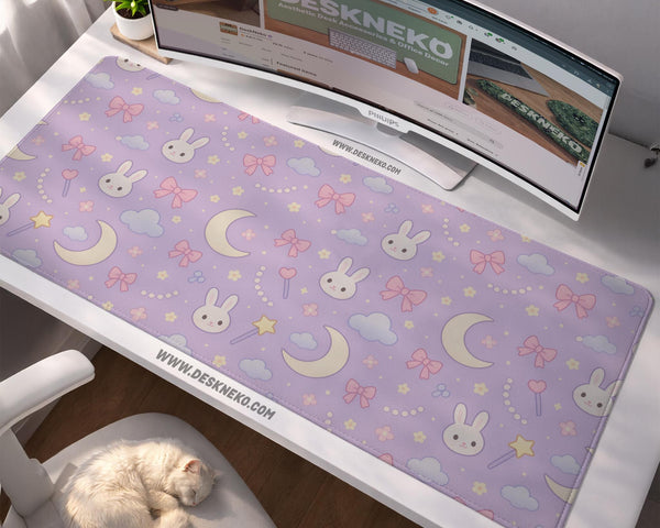 Lavender desk mat with an all-over pattern of bunny faces, clouds, moons, bows, and flowers in pastel colors.