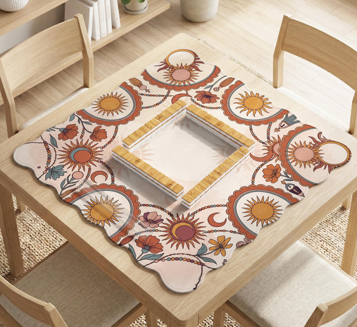 A square mahjong mat with a scalloped edge, sun and moon artwork, terracotta flowers, a soft cream background, and a decorative border around the play area.