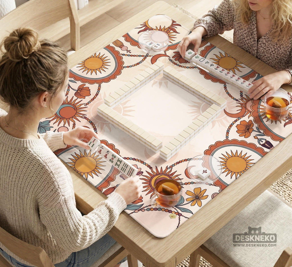 A square mahjong mat with a scalloped edge, sun and moon artwork, terracotta flowers, a soft cream background, and a decorative border around the play area.