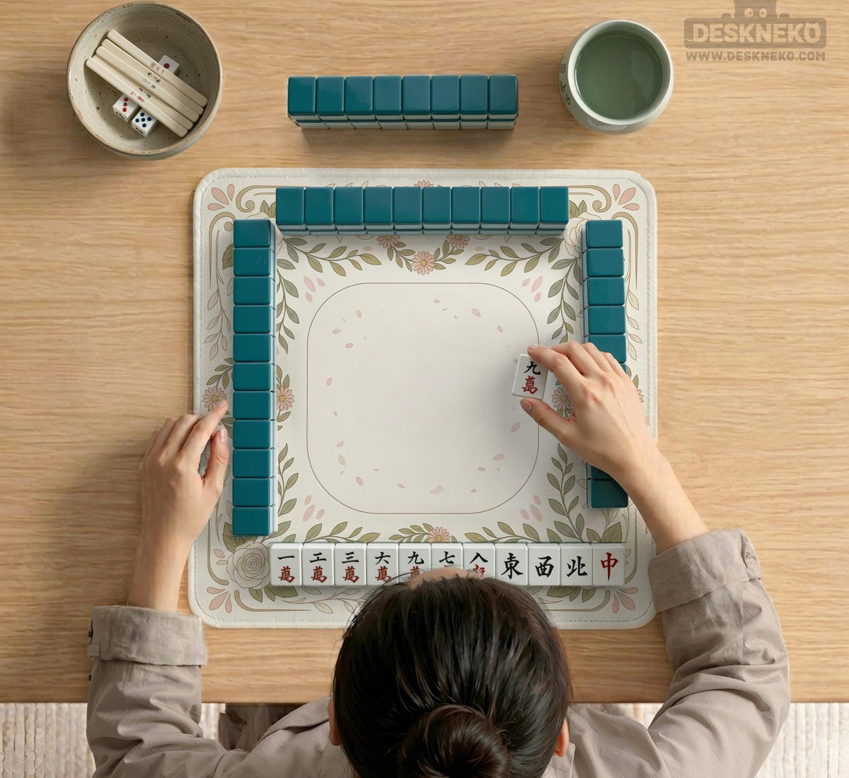Square mahjong mat with a light floral border in sage green, cream, and blush around a plain center play area.