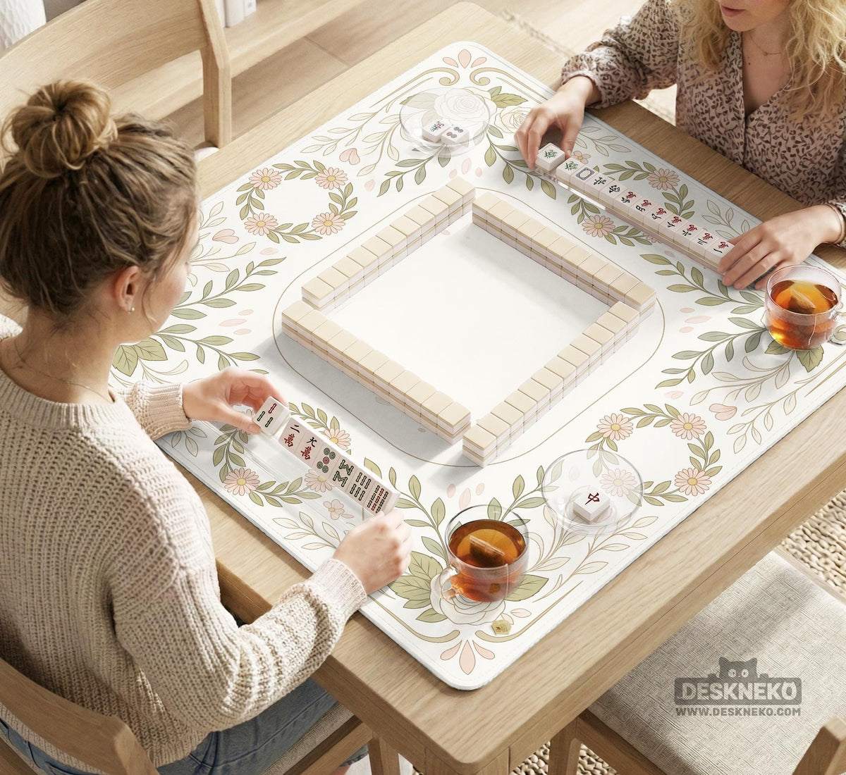 Square mahjong mat with a light floral border in sage green, cream, and blush around a plain center play area.