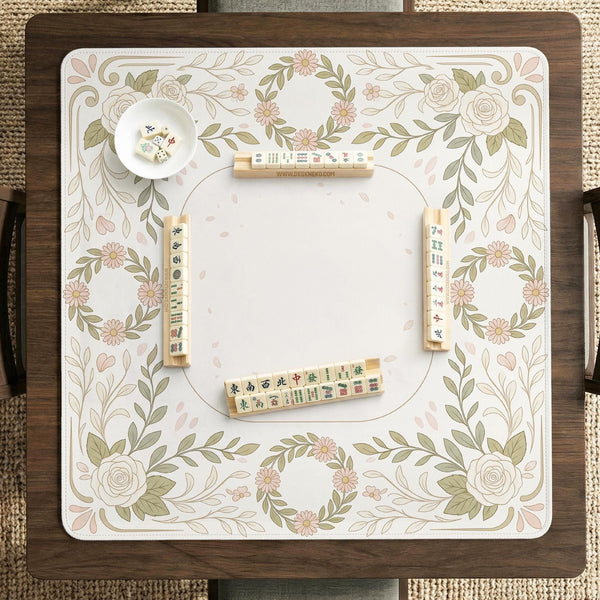 Square mahjong mat with a light floral border in sage green, cream, and blush around a plain center play area.
