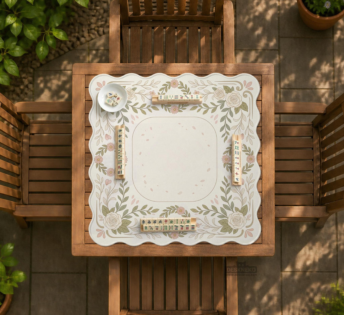 Square mahjong mat with a light floral border in sage green, cream, and blush around a plain center play area.