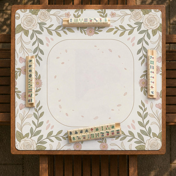 Square mahjong mat with a light floral border in sage green, cream, and blush around a plain center play area.
