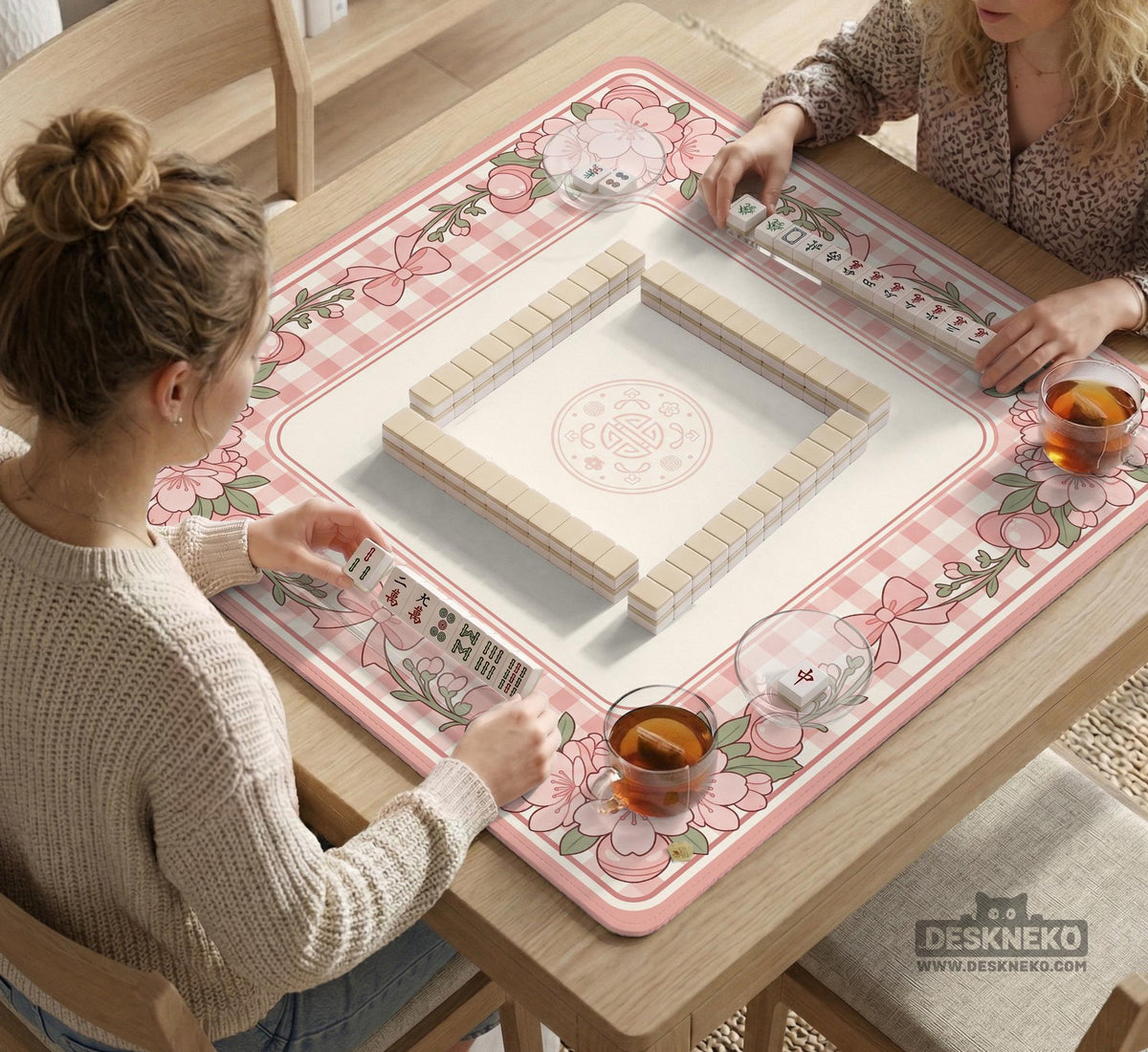 Pink gingham mahjong mat with a floral border, cherry blossom details, and a bow design around a plain center play area.