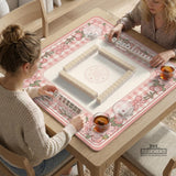 Square pink mahjong mat with a gingham border, floral corner details, and ribbon accents on a light background.