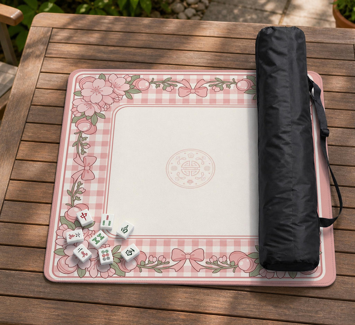 Pink gingham mahjong mat with a floral border, cherry blossom details, and a bow design around a plain center play area.