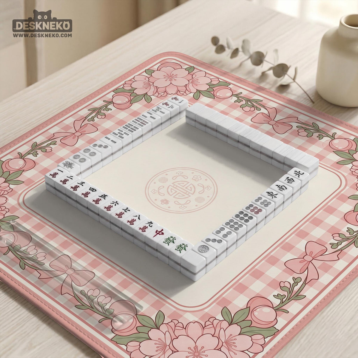 Pink gingham mahjong mat with a floral border, cherry blossom details, and a bow design around a plain center play area.