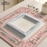 Pink gingham mahjong mat with a floral border, cherry blossom details, and a bow design around a plain center play area.