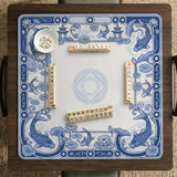 Navy blue square mahjong table mat with lotus flowers and koi fish in a porcelain-style border and a plain center.