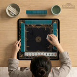 Square black mahjong mat with gold dragon artwork around the border and a light marble texture in the center.