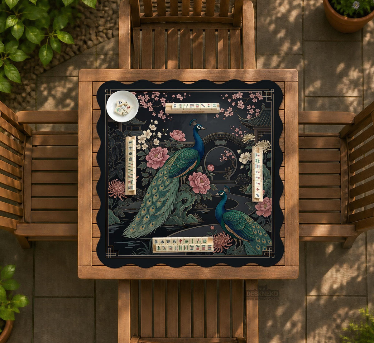 Square black mahjong mat with a gold peacock, blush flowers, and dark botanical artwork on a dark background.