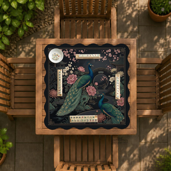 Square black mahjong mat with a gold peacock, blush flowers, and dark botanical artwork on a dark background.