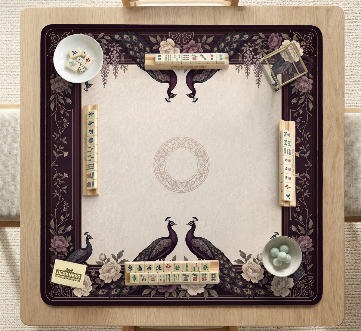 Square mahjong mat with a dark plum border, ivory floral pattern, muted sage leaves, and a decorative peacock garden design.