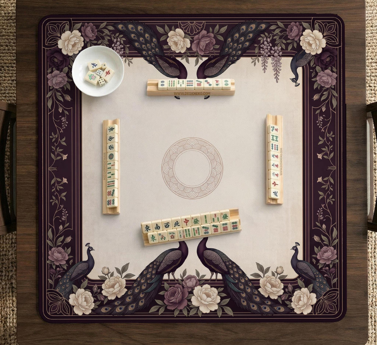 Square mahjong mat with a dark plum border, ivory floral pattern, muted sage leaves, and a decorative peacock garden design.