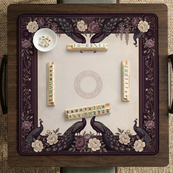 Square mahjong mat with a dark plum border, ivory floral pattern, muted sage leaves, and a decorative peacock garden design.