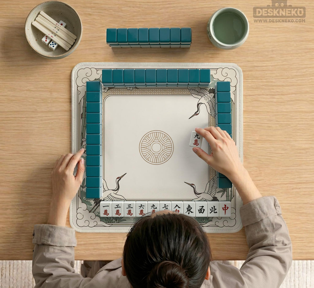 Square mahjong table mat with a cream center and a border design of cranes, bamboo, plum blossoms, and a geometric frame in sage green and warm gold.