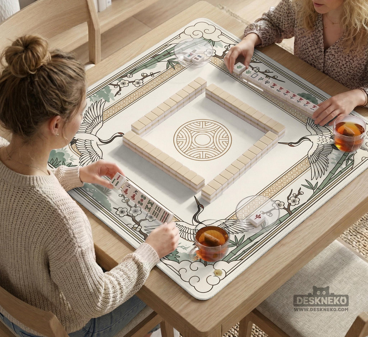 Square mahjong table mat with a cream center and a border design of cranes, bamboo, plum blossoms, and a geometric frame in sage green and warm gold.